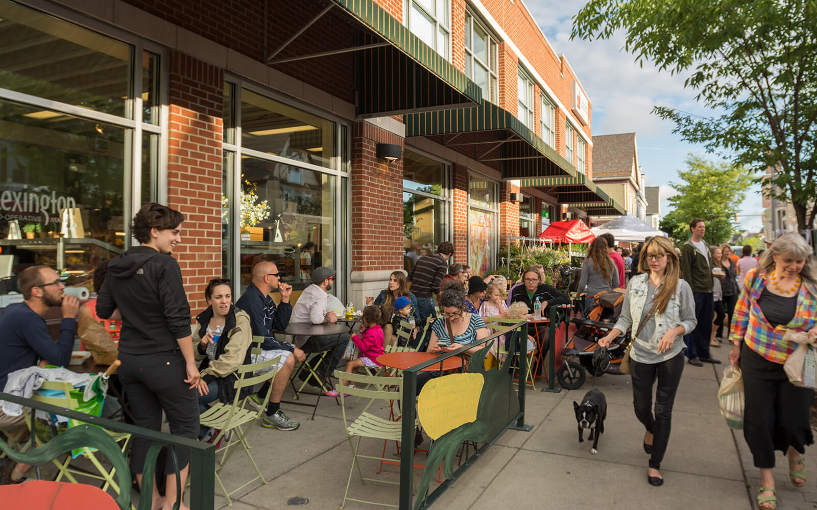 A bustling sidewalk with outdoor cafe seating in the Elmwood Village neighborhood in Buffalo, NY